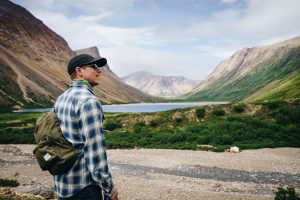 Dr. Michael Wahl, on the left side of the frame, stands surrounded by mountains, trees and blue skies.